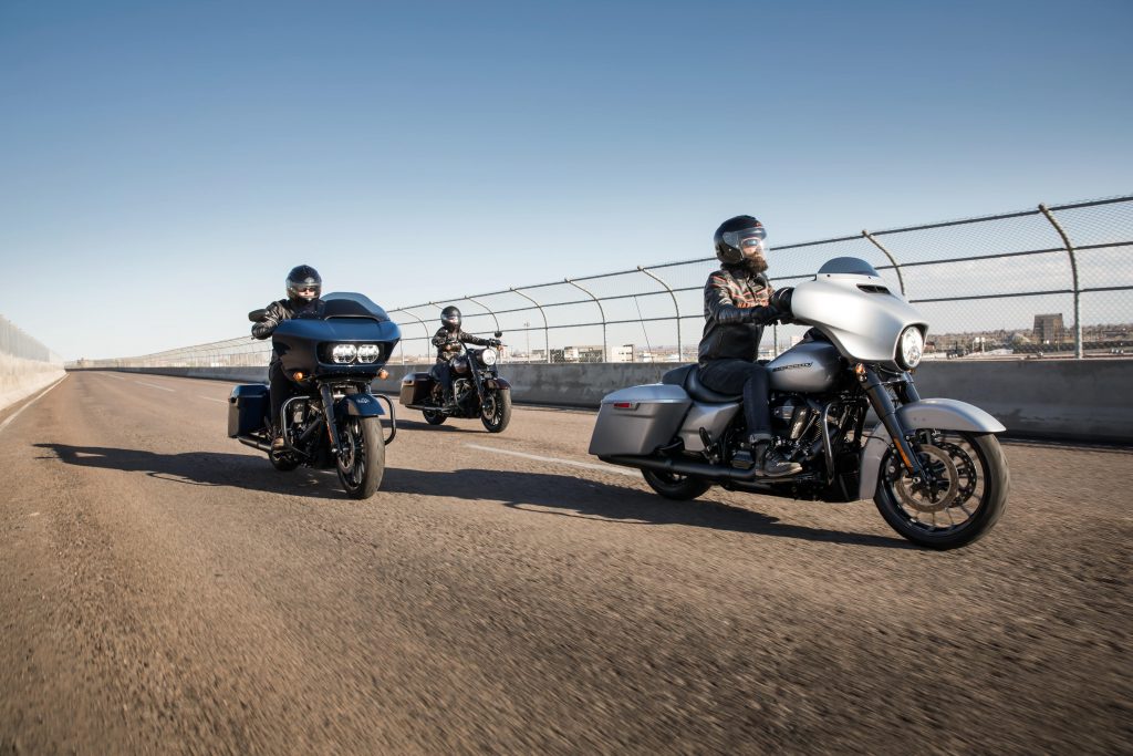 three men riding touring motorcycles on road using horns to notify other vehicles